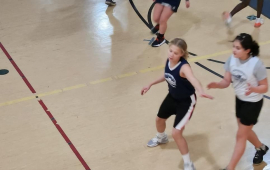 Youth Girls Basketball team playing game in gym in 2024