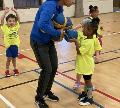 Boys and girls ages three to six are playing basketball in the Riverfront Community Center gym