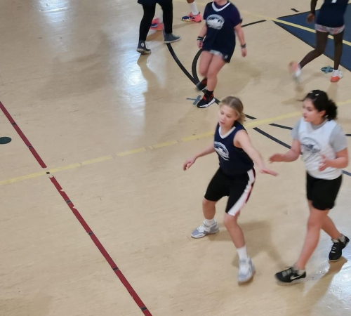 Group of girls grades first through sixth playing basketball in the riverfront gym