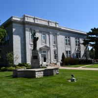 Leavenworth City Hall Photo of outside City hall, stone facade with green grass and trees, mini statue of liberty