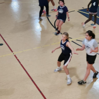 Youth Girls Basketball team playing game in gym in 2024