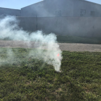 Photo of smoke coming out of a manhole in a green field outside