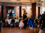A little girl in a pink dress dancing with her dad in 2022