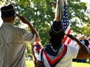 Salute two people wearing veteran's hats salute an American flag