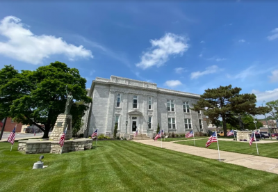 photo of historic building with columns and statues with a blue sky and freshly mowed lawn