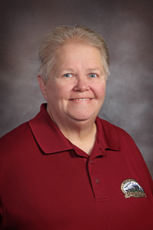 Photo of woman with gray hair in red shirt with City of Leavenworth logo