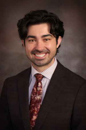 Man with black wavy hair wearing a business suit and neck tie