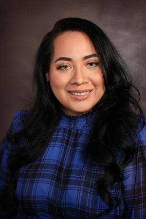 Woman with long black wavy black hair wearing a blue blouse