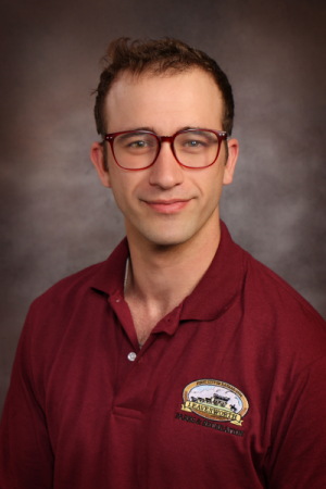 Man with brown hair and glasses wearing red collared shirt with City of Leavenworth patch on his shoulder