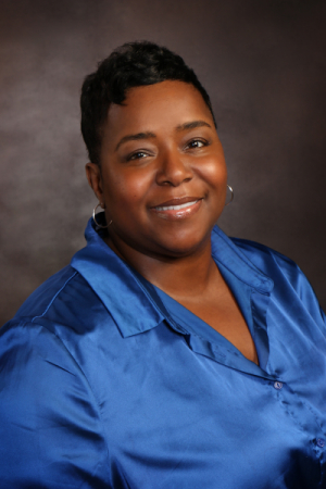 Woman with short heavily curled black hair wearing blue blouse
