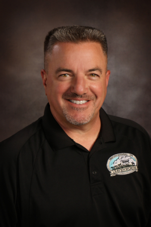 Main with short brown hair, moustache wearing a black collared shirt with a city of Leavenworth logo on the shoulder