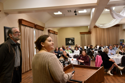 Public Works Director Brian Faust and Planning and Community Development Director Kim Portillo talk to audience at Business Symposium man and woman speak in front of podium to address audience seated at tables inside room