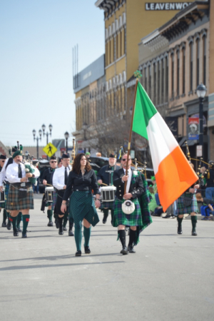 People carry Irish flag on downtown street wearing traditional irish clothes and kilts