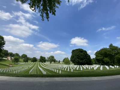 Photo of well kept cemetery in a green field with blue sky and trees