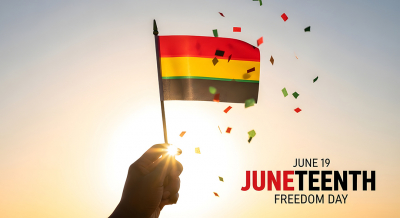 Juneteenth hand reaches for small flag with bands of red, yellow and green surrounded by confetti with text June 19 Juneteenth Freedom day
