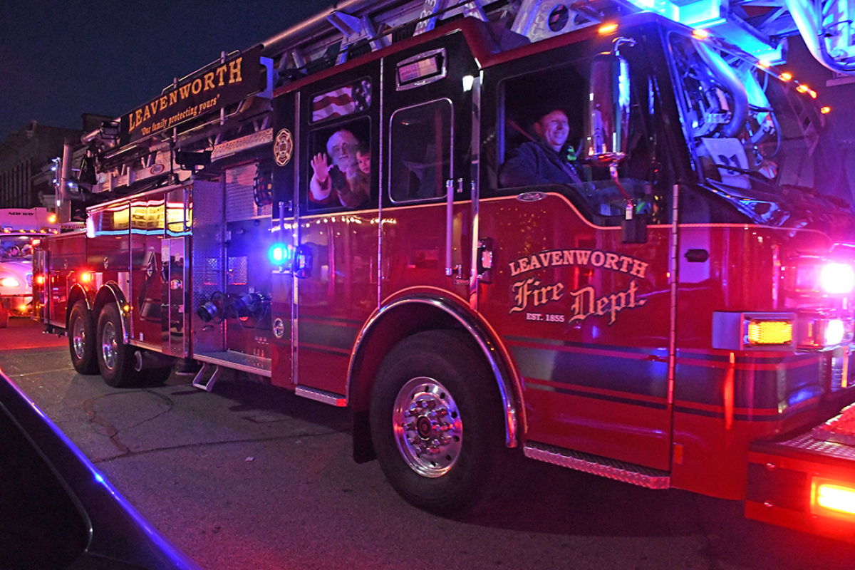 lighted parade santa and child wave from inside a fire truck
