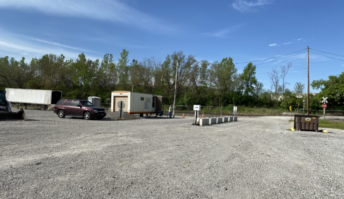 Entrance to the Leavenworth Brush Site, several piles of brush and yard waste on a gravel lot with a trailer office and vehicles