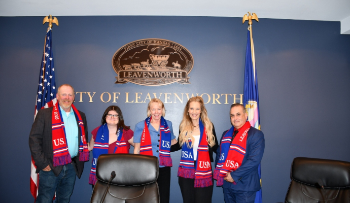 Five elected city commissioners pose with FIFA scarves in front of City logo