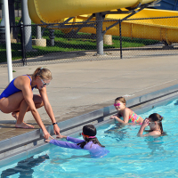 Assistant Manger teaching swim lessons to three children at Wollman Aquatic Center